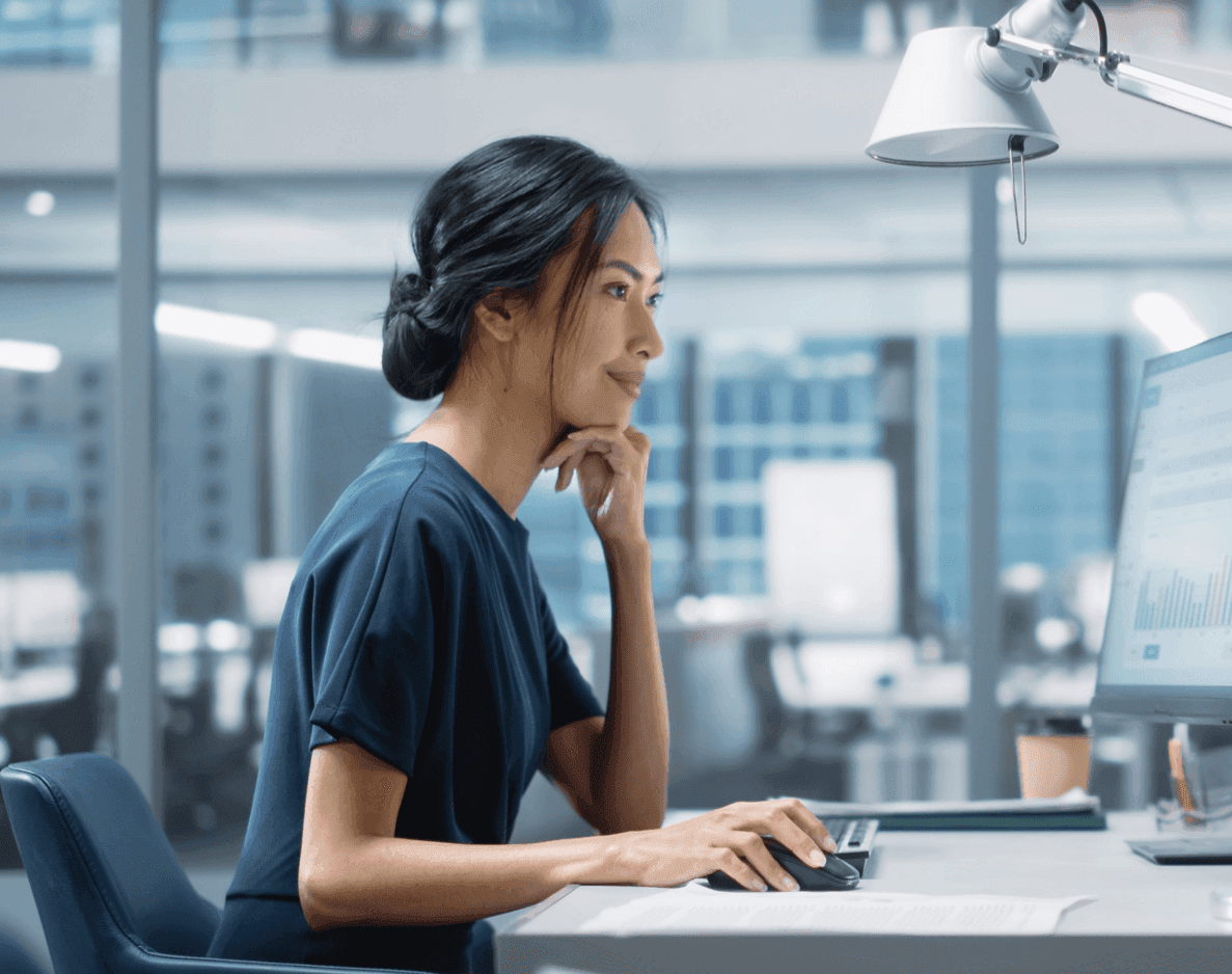Professional woman working diligently at a desktop computer in a modern office.
