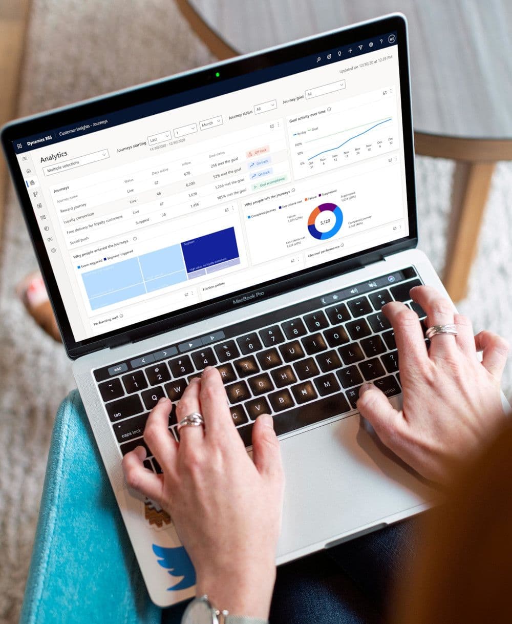 Person typing on a laptop displaying data analytics and charts on the screen.